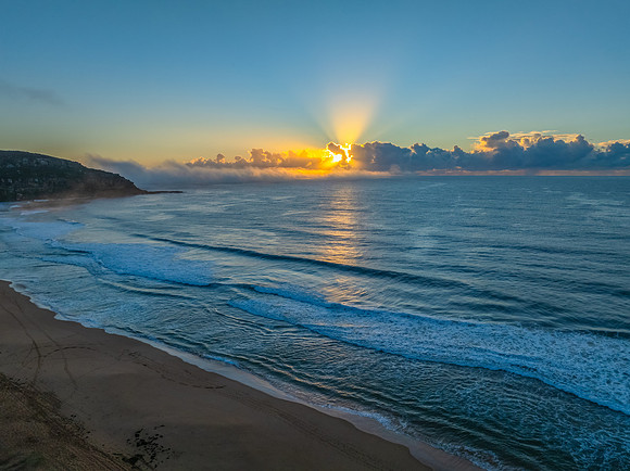 Sunrise over the sea with a low cloud bank and fog