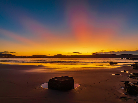Aerial sunrise at the beach with sun rays in a clear sky