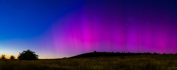 Aurora Australis display lights up the predawn sky in pinks