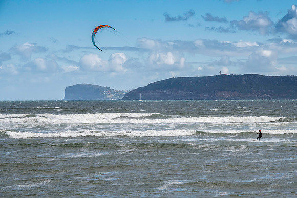 Windsurfers riding the waves on a wild day at the beach