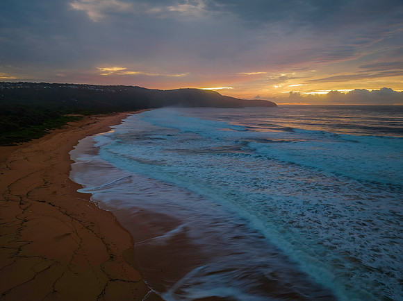 Cloud covered sunrise at the seaside in pink and blue