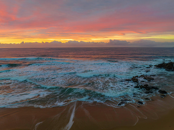 Cloud covered sunrise at the seaside in pink and blue