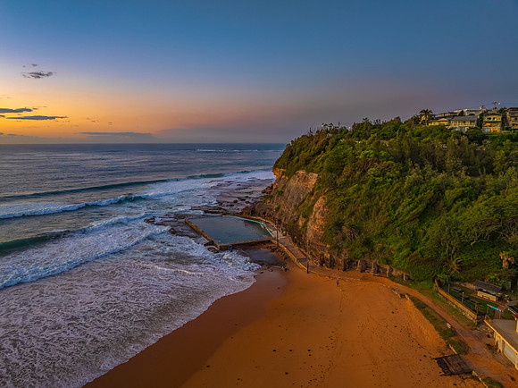 Sunrise at the beach with waves and a smattering of clouds