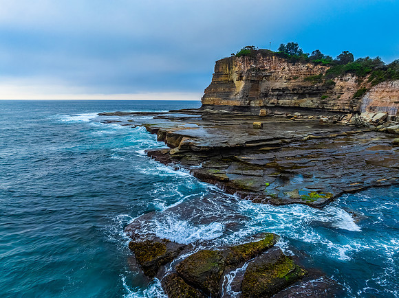 Sunrise seascape and rocky Inlet with thick fog cloud over the o