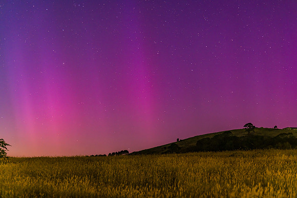 Aurora Australis display lights up the predawn sky in pinks