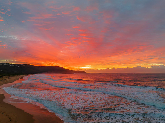 Cloud covered sunrise at the seaside in pink and blue