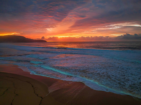Cloud covered sunrise at the seaside in pink and blue