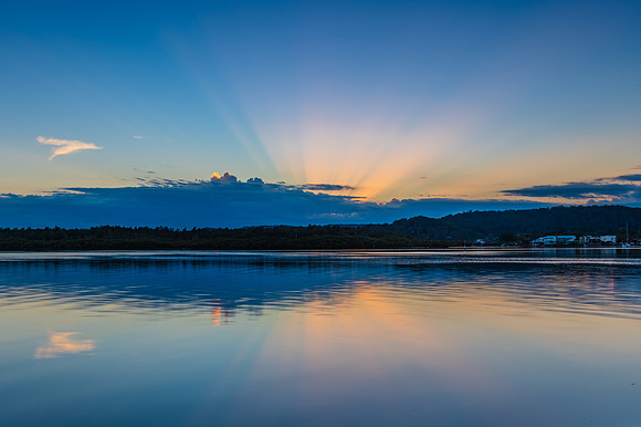Sunrise waterscape with cloud reflections and sun rays