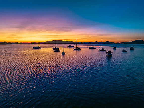 Aerial sunrise waterscape with boats and high cloud