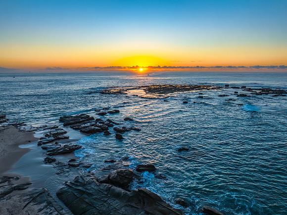Sunrise over the sea and rocks with clear skies
