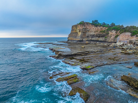 Sunrise seascape and rocky Inlet with thick fog cloud over the o
