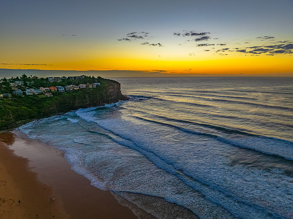 Sunrise at the beach with waves and a smattering of clouds