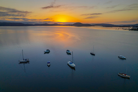 Sunrise waterscape with boats, soft clouds and reflections