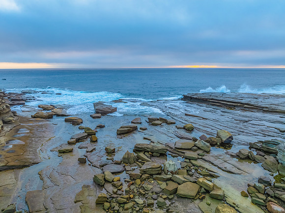 Sunrise seascape and rocky Inlet with thick fog cloud over the o