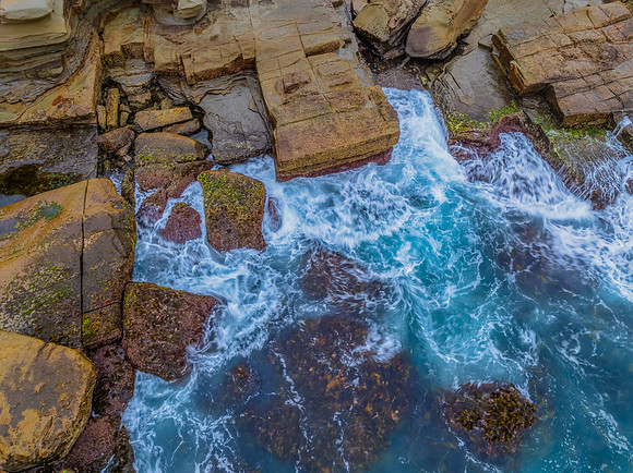 Sunrise and the blue sea washing over the rock platform