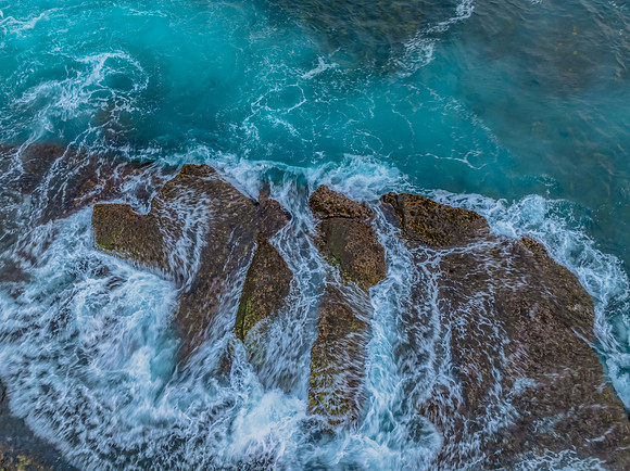 Sunrise and the blue sea washing over the rock platform