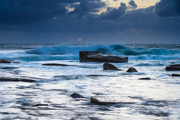 Moody sunrise seascape with clouds at the rocky inlet