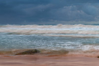 Sunrise at the seaside with rocks and rain clouds