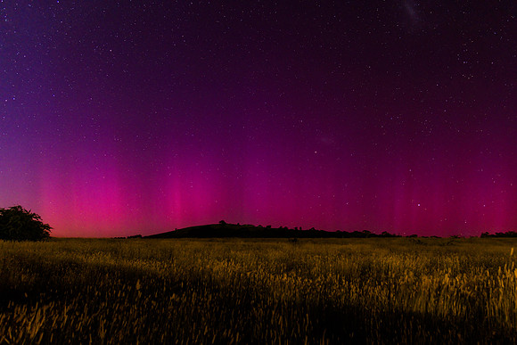 Aurora Australis display lights up the predawn sky in pinks