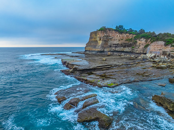 Sunrise seascape and rocky Inlet with thick fog cloud over the o