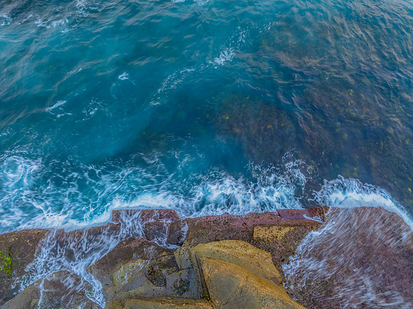 Sunrise and the blue sea washing over the rock platform
