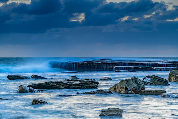 Moody sunrise seascape with clouds and casscades over the rock p