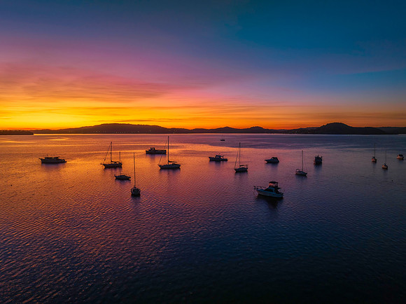 Aerial sunrise waterscape with boats and high cloud