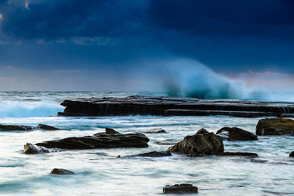 Moody sunrise seascape with clouds and casscades over the rock p