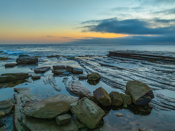 Sunrise seascape and rocky Inlet with thick fog cloud over the o