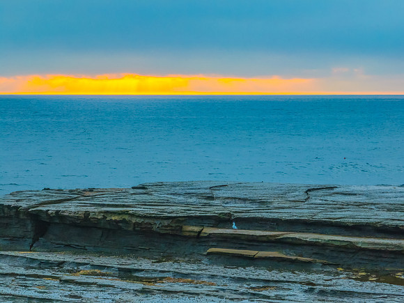 Sunrise seascape and rocky Inlet with thick fog cloud over the o