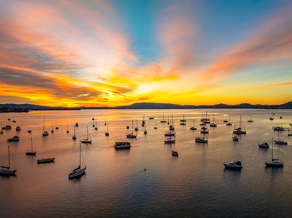 Aerial sunrise waterscape with boats and high cloud