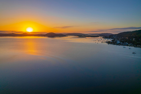 Sunrise waterscape with boats, soft clouds and reflections