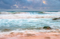 Sunrise at the seaside with rocks and rain clouds