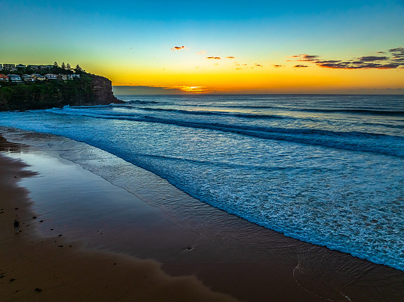 Sunrise at the beach with waves and a smattering of clouds