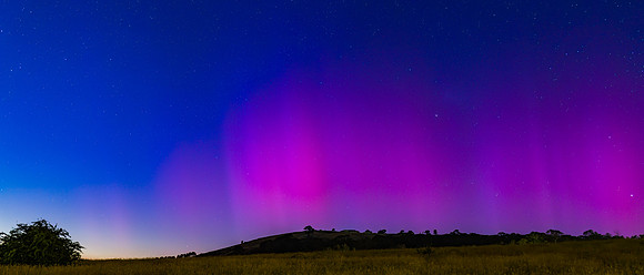 Aurora Australis display lights up the predawn sky in pinks