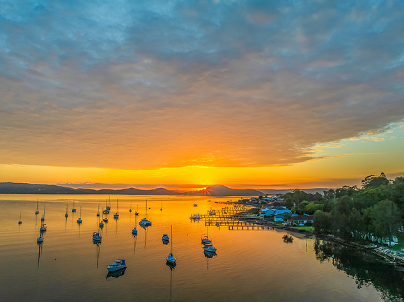 Aerial sunrise over the water with boats and clouds