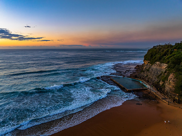 Sunrise at the beach with waves and a smattering of clouds