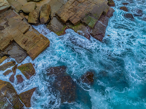 Sunrise and the blue sea washing over the rock platform