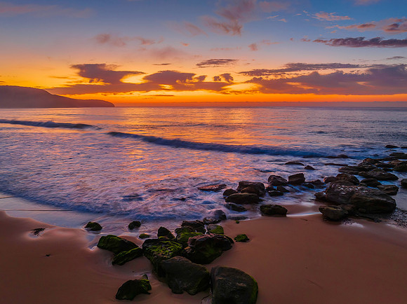 Peaceful sunrise over the ocean with small waves and clouds