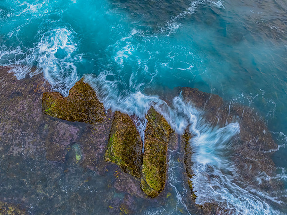 Sunrise and the blue sea washing over the rock platform