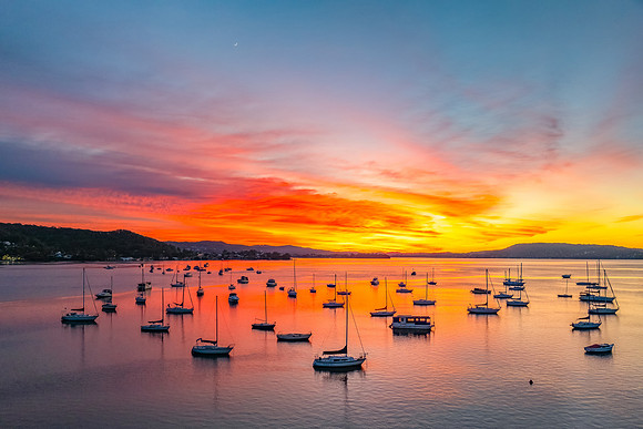 Aerial sunrise waterscape with boats and high cloud