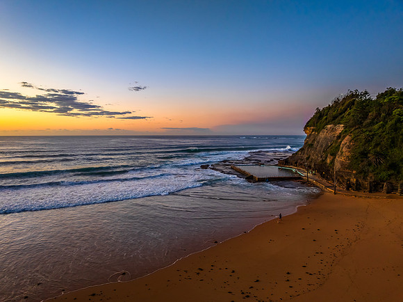 Sunrise at the beach with waves and a smattering of clouds