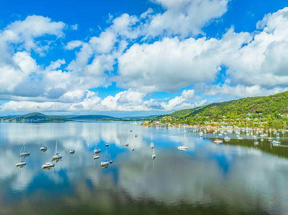 Aerial views over the bay with clouds, reflections and boats