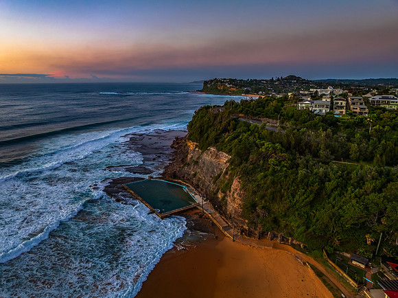 Sunrise at the beach with waves and a smattering of clouds
