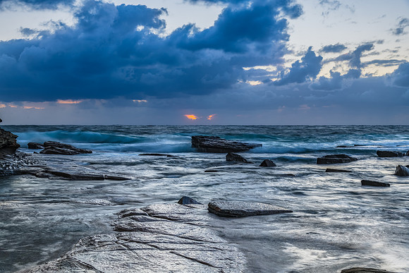 Moody sunrise seascape with clouds at the rocky inlet