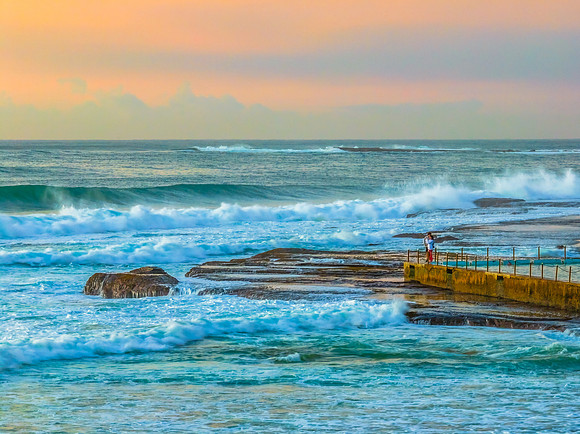 Sunrise at the beach with waves and a smattering of clouds