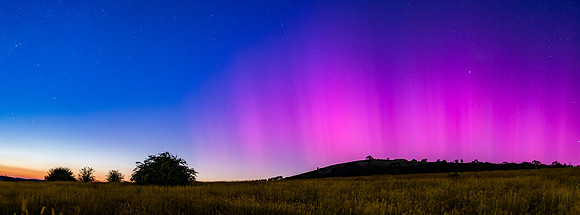 Aurora Australis display lights up the predawn sky in pinks