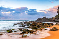 Sunrise at the seaside with rocks and rain clouds