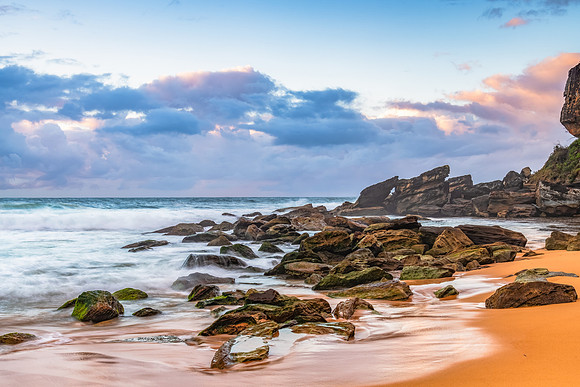 Sunrise at the seaside with rocks and rain clouds