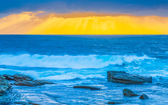 Moody sunrise seascape with clouds and sunrays at the rocky inle